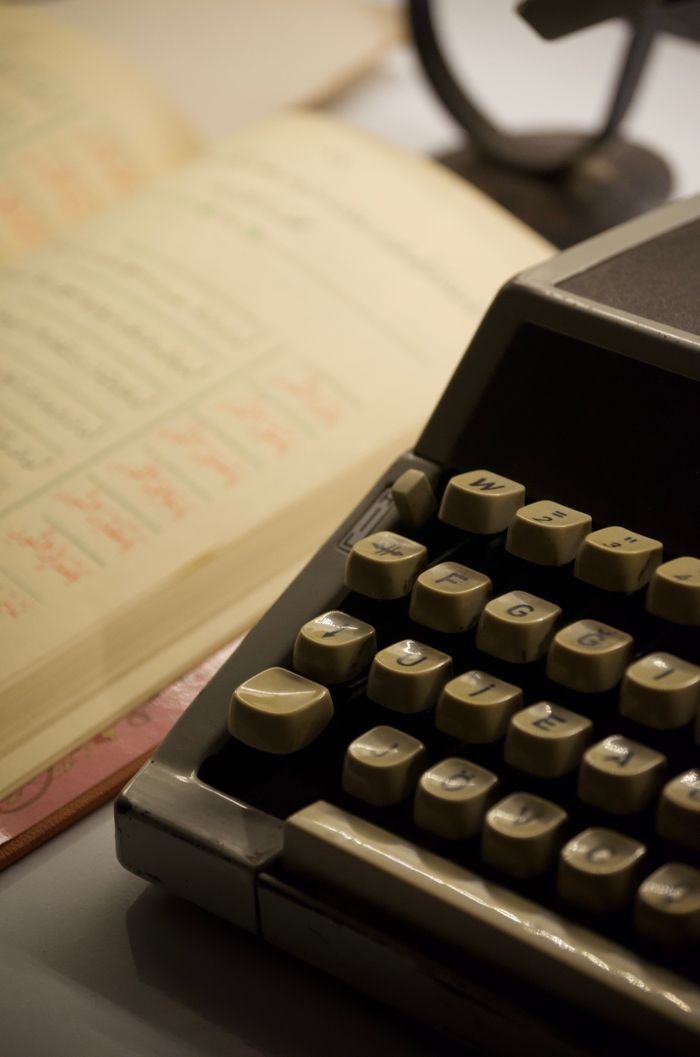 Close-up of an old typewriter and ledger, evoking a vintage office setting.
